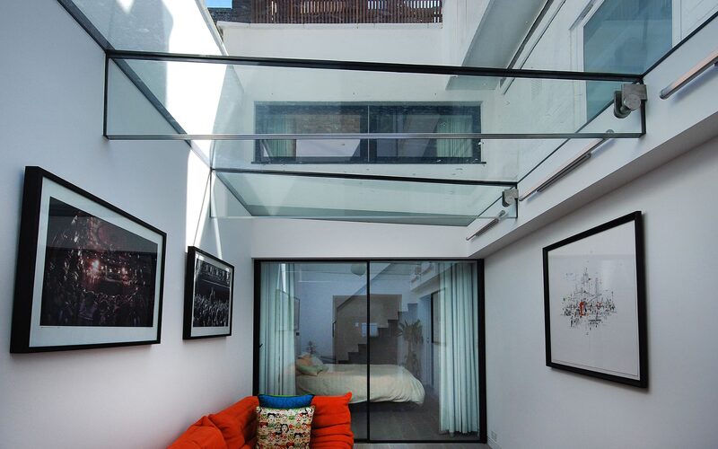an internal view of a structural glass roof spanning between two white render walls - glass roofs